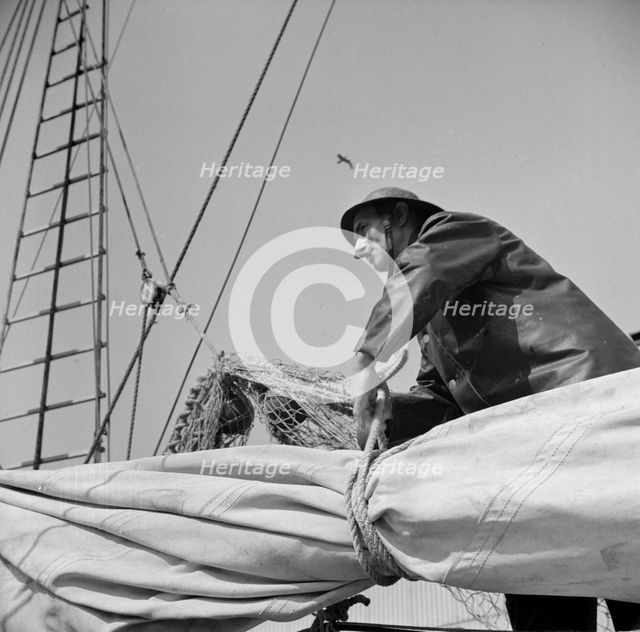 Possibly:  A New England fisherman preparing his boat to leave the New York docks, 1943. Creator: Gordon Parks.