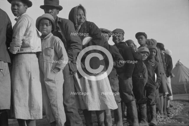 Possibly: Negroes in the lineup for food at the flood refugee camp, Forrest City, Arkansas, 1937. Creator: Walker Evans.