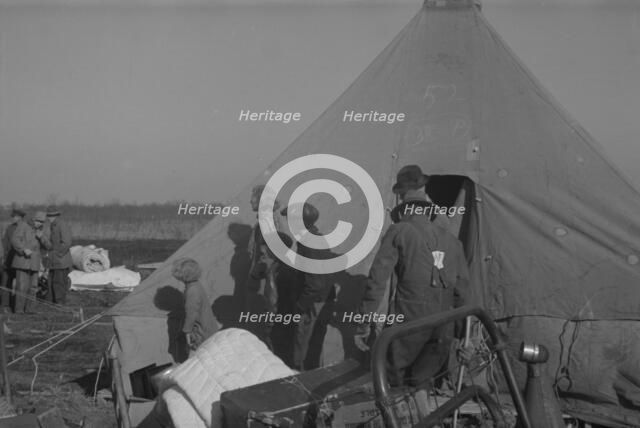 Possibly: Setting up a tent in the camp for white flood refugees, Forrest City, Arkansas, 1937. Creator: Walker Evans.