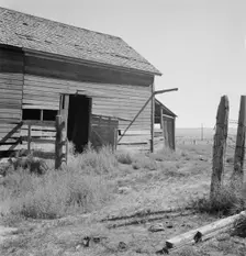 Possibly: Weeds crowd the barn door abandoned in Columbian Basin, Grant County, Washington, 1939. Creator: Dorothea Lange