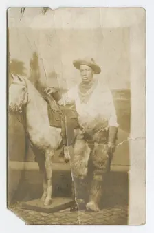 Postcard of a man posing in a Western scene in a photography studio, early 20th century. Creator: Unknown