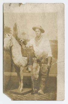 Postcard of a man posing in a Western scene in a photography studio, early 20th century. Creator: Unknown
