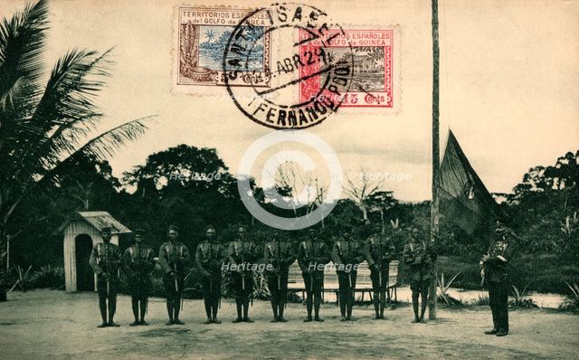 Postcard. St. Elizabeth of Fernando Poo. Flag hoisting by the colonial guard at the Assobla post,…