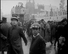 Packed Pavement on a British Street. Behind the Pedestrians Is a Sign Reading Site for..., 1921. Creator: British Pathe Ltd
