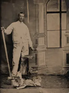 [Painter, Standing in Front of a Painted Window Backdrop, with Brushes, Bucket, and P..., 1870s-80s. Creator: Unknown