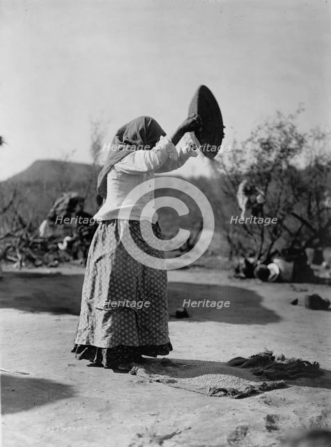 Papago cleaning wheat (Winnowing wheat), c1907. Creator: Edward Sheriff Curtis.
