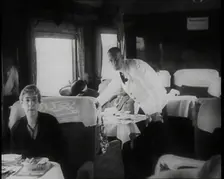 Passengers Sitting in the Dining Car of a Train as They Are Waited on by Attendants, 1938. Creator: British Pathe Ltd