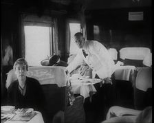 Passengers Sitting in the Dining Car of a Train as They Are Waited on by Attendants, 1938. Creator: British Pathe Ltd
