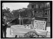 Peanut vendor Steve Vasilakas standing near his cart..., between 1916 and 1918. Creator: Harris & Ewing