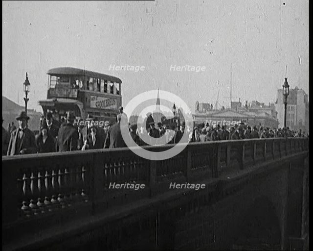 Pedestrians And Commuters Crossing London Bridge With Buses in the Background, 1920s. Creator: British Pathe Ltd.