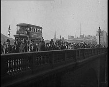 Pedestrians And Commuters Crossing London Bridge With Buses in the Background, 1920s. Creator: British Pathe Ltd