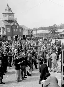 People attending a motor racing event at Brooklands. Artist: Bill Brunell