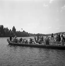 People arrive in long boats, called church boats, for the Midsummer celebrations, Sweden, 1941. Creator: Torkel Lindeberg