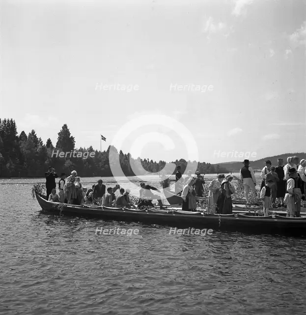 People arrive in long boats, called church boats, for the Midsummer celebrations, Sweden, 1941. Creator: Torkel Lindeberg.