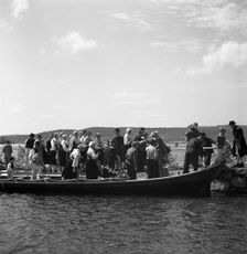 People arrive in long boats, called church boats, Midsummer's Eve and Day celebrations, 1941. Creator: Torkel Lindeberg