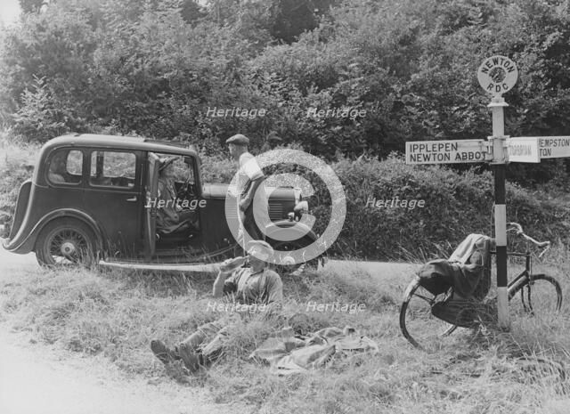 People relaxing by a signpost with a 1935 Standard 10 hp car, Devon, (c1935?). Artist: Unknown