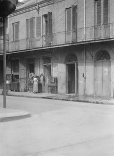 People standing by the doorway of a furniture shop in the French Quarter, New Orleans, c1920-1926. Creator: Arnold Genthe