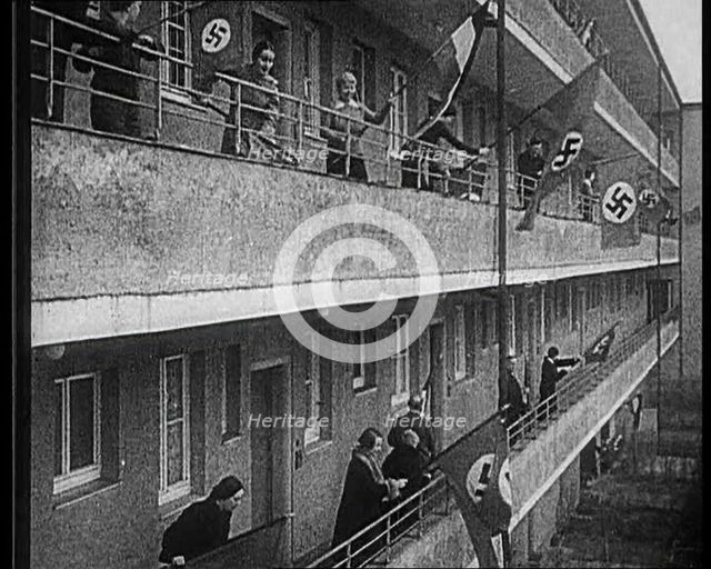 People Waving Flags of the Nazi Party and German Flags of 1867-1918 from Balconies, 1933. Creator: British Pathe Ltd.