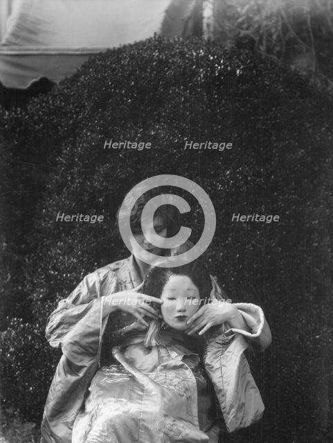 Person holding a mask made by W.T. Benda, 1925 Sept. 20. Creator: Arnold Genthe.