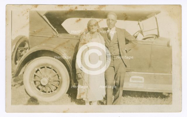 Photograph of a man and woman in front of car, ca. 1921. Creator: Unknown.