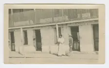 Photograph of a man and woman standing on a sidewalk, early 20th century. Creator: Unknown