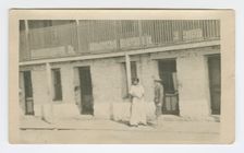 Photograph of a man and woman standing on a sidewalk, early 20th century. Creator: Unknown