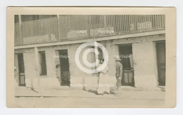 Photograph of a man and woman standing on a sidewalk, early 20th century. Creator: Unknown.