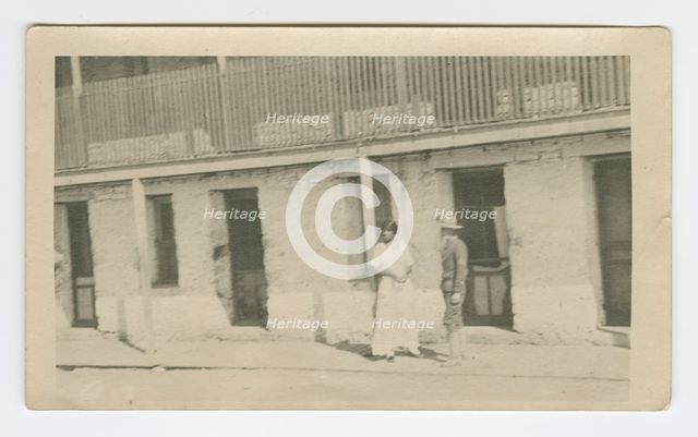 Photograph of a man and woman standing on a sidewalk, early 20th century. Creator: Unknown.