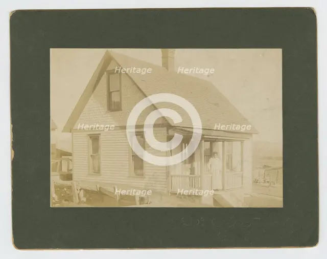 Photograph of a woman standing on the porch of a house, early 20th century. Creator: Unknown.