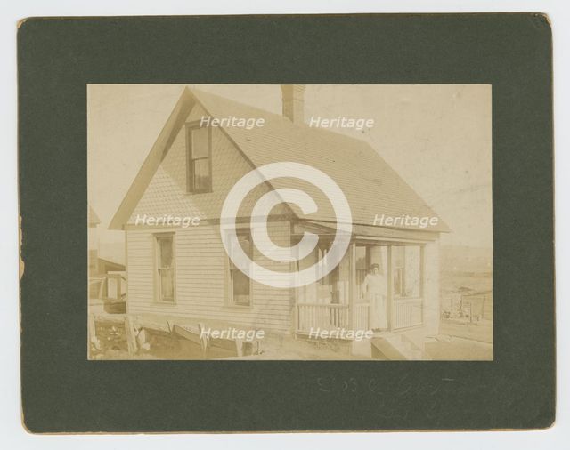 Photograph of a woman standing on the porch of a house, early 20th century. Creator: Unknown.