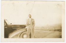 Photograph of an unidentified man in front of car, ca. 1920. Creator: Unknown