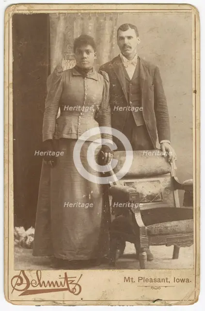 Photograph of an African-American couple standing behind a chair, ca. 1890. Creator: Schmitz Studio.