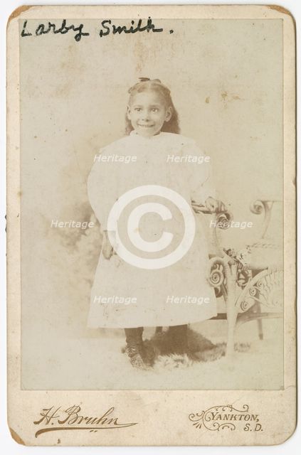 Photograph of Larby Smith standing next to a wicker chair., late 19th century. Creator: Henry Bruhn.