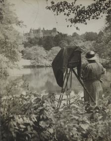 Photographer Frances Benjamin Johnston standing beside her large view camera looking..., c1938. Creator: Unknown
