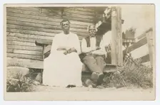 Photographic postcard of an elderly couple sitting on a porch, 1904-1929. Creator: Unknown