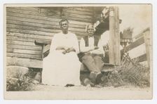 Photographic postcard of an elderly couple sitting on a porch, 1904-1929. Creator: Unknown