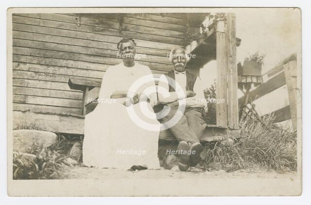 Photographic postcard of an elderly couple sitting on a porch, 1904-1929. Creator: Unknown.