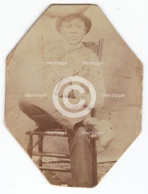 Photographic print of a man in suit sitting on a chair with right leg crossed, late 19th-early 20th  Creator: Unknown.