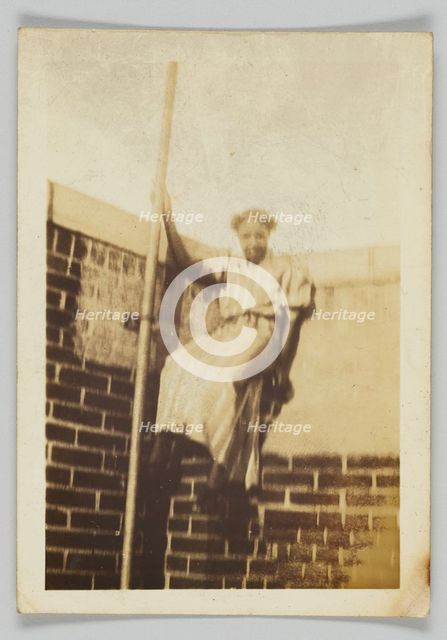 Photographic print of a woman on a brick wall, early 20th century. Creator: Unknown.