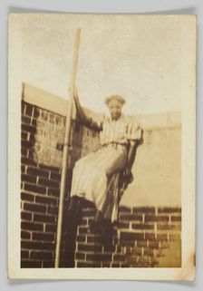 Photographic print of a woman on a brick wall, early 20th century. Creator: Unknown
