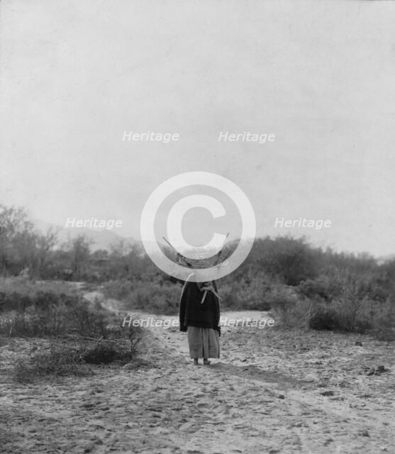 Pima woman, with burden basket on back, walking away from camera, Pima, Arizona, c1907. Creator: Edward Sheriff Curtis.