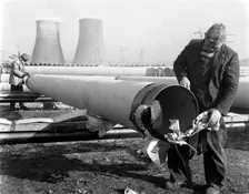 Pipe wrapping to prevent corrosion on steel pipes, Old Denaby, South Yorkshire, 1961. Creator: Michael Walters