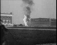 Plume of Flame Emitting from the Bellanca Crash as People Attend to Wreckage, 1933. Creator: British Pathe Ltd