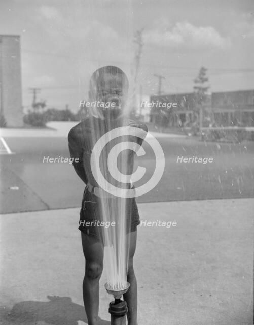 Playing in the community sprayer, Frederick Douglass housing project, Anacostia, D.C., 1942. Creator: Gordon Parks.