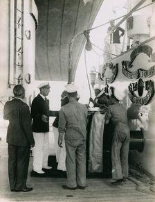 Preparing to hoist a case from the deck of H.M.S. Suffolk at Portsmouth, July 1935. Creator: Topical Press Agency