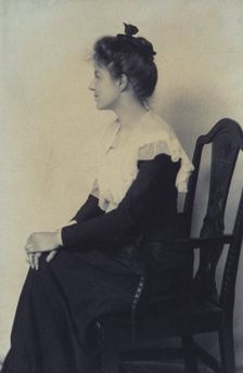 Profile portrait of a woman seated in chair, facing left with hands on her knees, c1900. Creator: Misses Selby