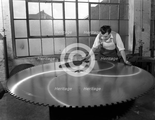Quality checking a giant saw blade, Edgar Allen's steel foundry, Sheffield, South Yorkshire, 1963.  Creator: Michael Walters.