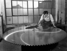 Quality checking a giant saw blade, Edgar Allen's steel foundry, Sheffield, South Yorkshire, 1963. Creator: Michael Walters