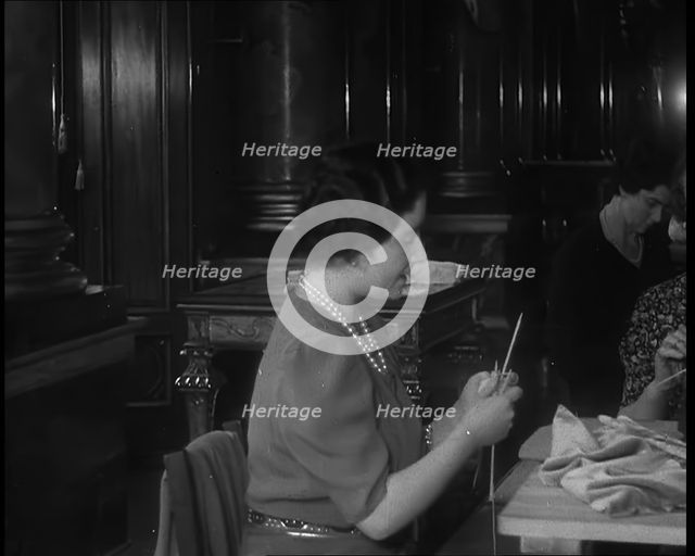 Queen Elizabeth Knitting at a Large Sewing Group Hosted in Buckingham Palace, 1940. Creator: British Pathe Ltd.