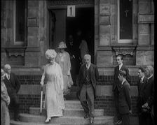Queen Mary Accompanied by a Group of Officials Emerging from a Building , 1924. Creator: British Pathe Ltd